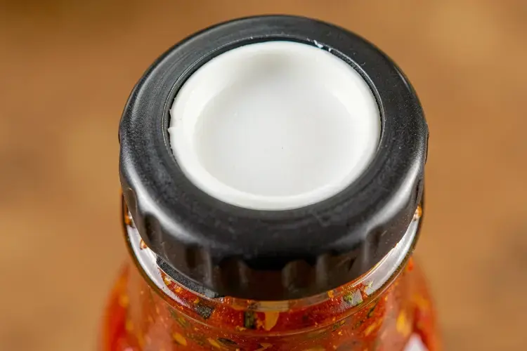 bagian dalam tutup lug cap seng yang menunjukkan lapisan karet plastisol putih kedap udara. alt lapisan plastisol liner pada tutup botol kaca sambal