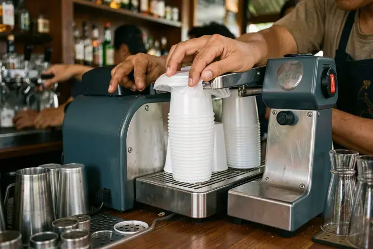 proses penyegelan otomatis cup plastik pp menggunakan mesin cup sealer pemanas elektrik di bar barista. alt proses penyegelan cup plastik denpasar dengan mesin sealer